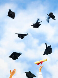 An image of University mortarboards and certificates being thrown into the air against sky.